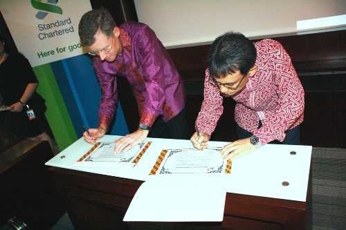 CEO Standard Chartered Bank, Tom Aaker, bersama President Direktur XL, Hasnul Suhaimi sedang melakukan penandatanganan kerjasama penyediaan layanan telekomunikasi korporat yang disediakan oleh XL untuk SCB